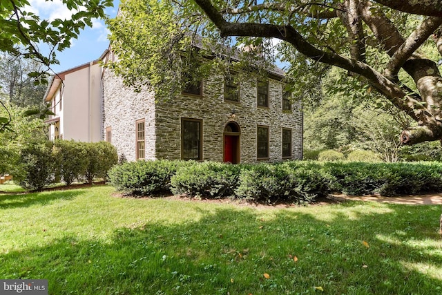 colonial home with stone siding and a front yard
