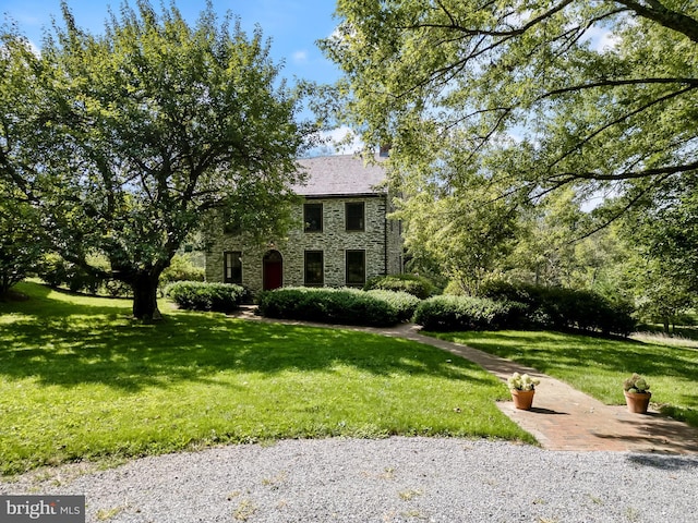 colonial home featuring stone siding and a front yard