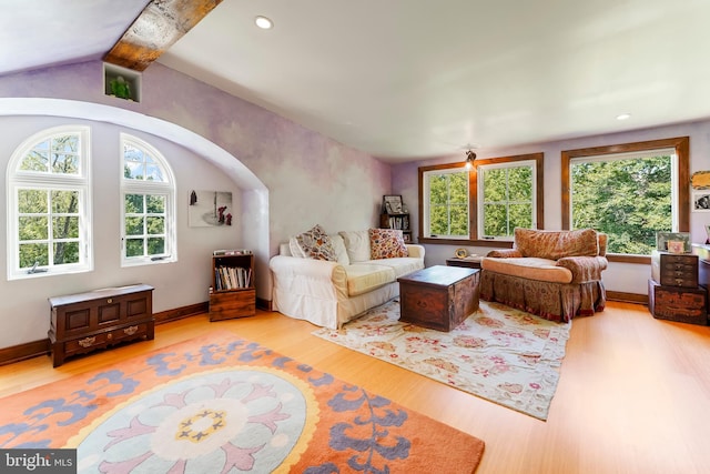 living room featuring lofted ceiling with beams, light hardwood / wood-style floors, and plenty of natural light