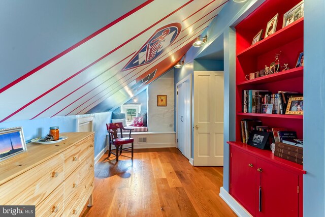 interior space featuring wood-type flooring, built in features, and vaulted ceiling