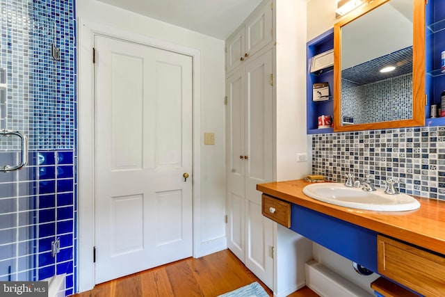 bathroom featuring vanity, tasteful backsplash, a shower with door, and wood finished floors