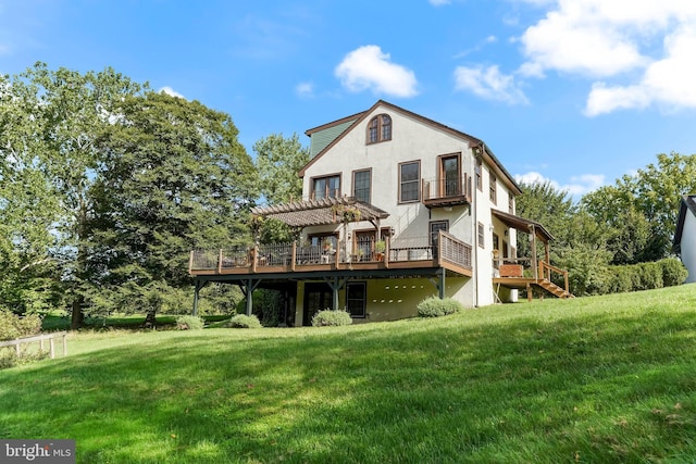 rear view of house with stucco siding, a lawn, a deck, and a pergola