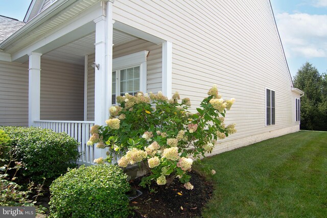 view of home's exterior with a lawn and covered porch