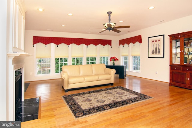 living room with recessed lighting, wood finished floors, a high end fireplace, and a healthy amount of sunlight