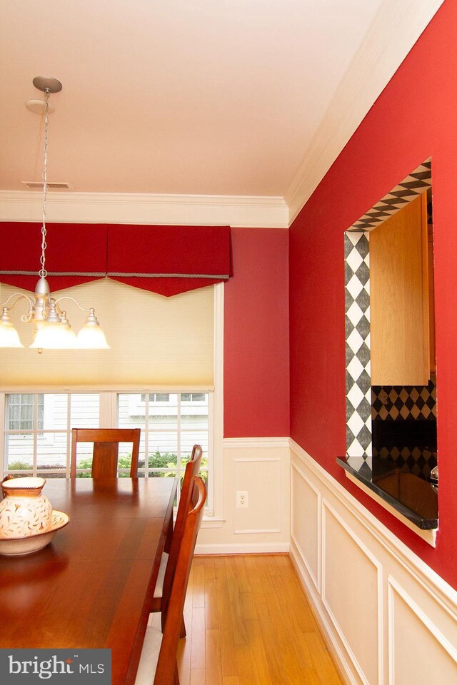 unfurnished dining area with light wood-type flooring, a chandelier, and ornamental molding