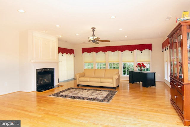 living area featuring a high end fireplace, light wood-style flooring, and recessed lighting