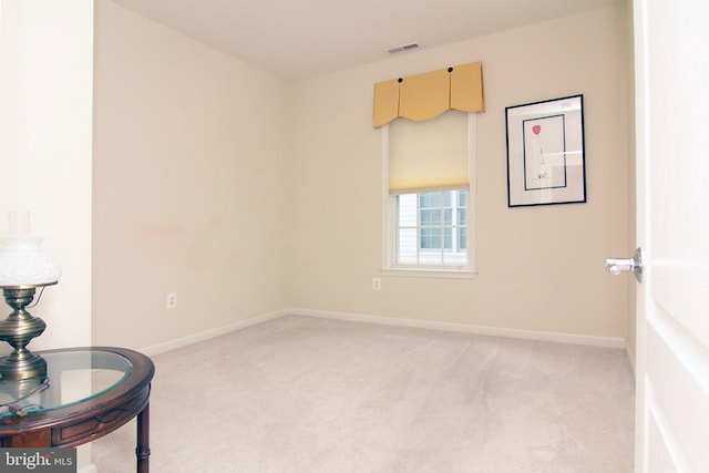 spare room with baseboards, visible vents, and light colored carpet