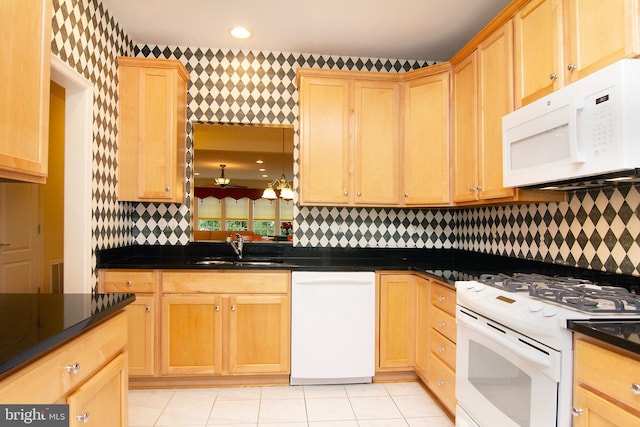 kitchen with dark countertops, white appliances, light brown cabinets, and wallpapered walls