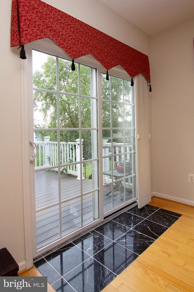 doorway to outside featuring baseboards and wood finished floors