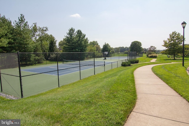 view of tennis court featuring a lawn and fence