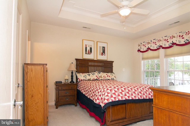 bedroom with ceiling fan, a raised ceiling, and light carpet