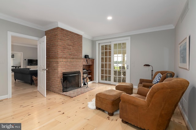 living room with crown molding, light hardwood / wood-style floors, and a brick fireplace