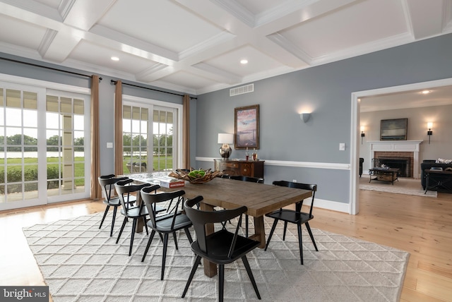 dining area with a brick fireplace, beam ceiling, light hardwood / wood-style floors, and coffered ceiling