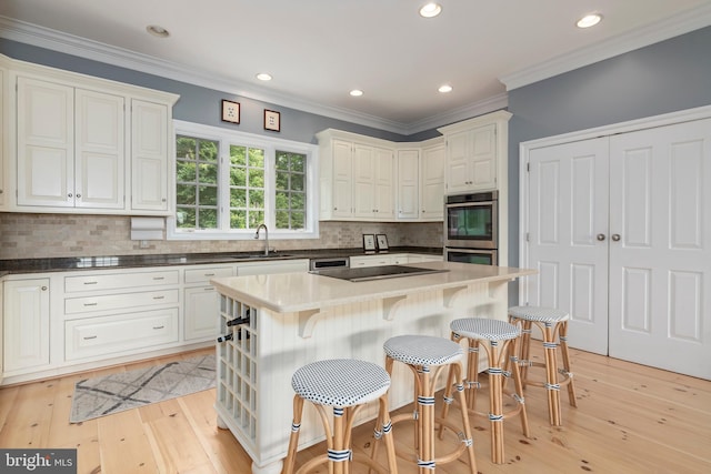 kitchen with decorative backsplash, appliances with stainless steel finishes, a kitchen breakfast bar, a kitchen island, and white cabinetry