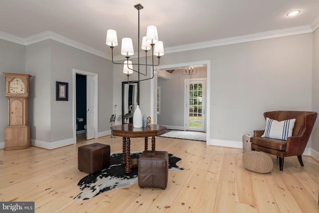 living area with light hardwood / wood-style floors, crown molding, and an inviting chandelier