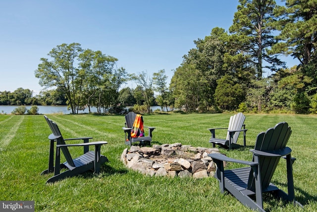 view of community featuring a lawn, a water view, and a fire pit