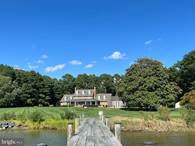 back of house featuring a lawn and a water view