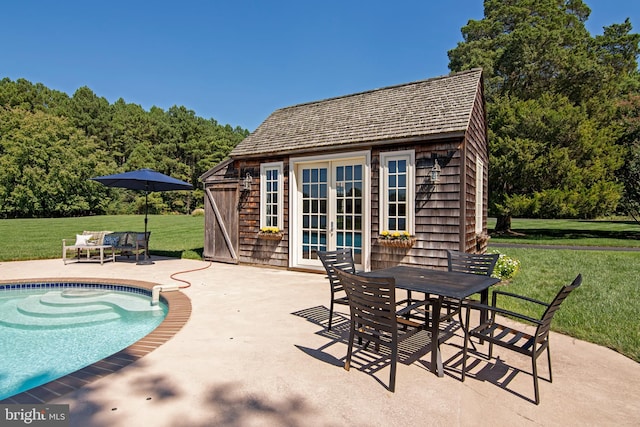 view of swimming pool with a patio, an outdoor structure, and a lawn