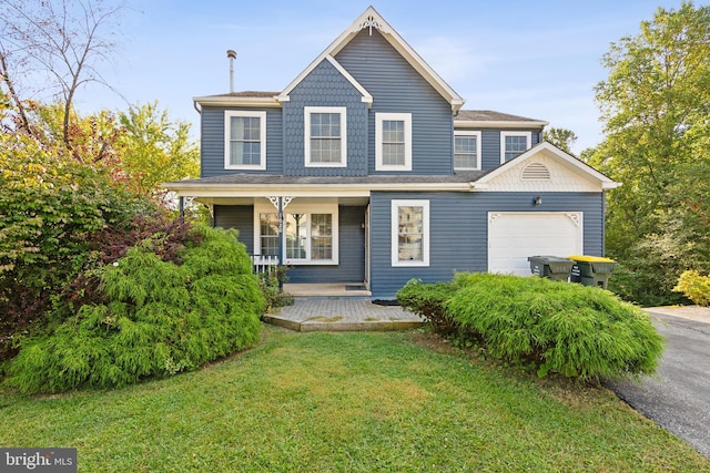 view of front of property featuring a porch, a front yard, and a garage