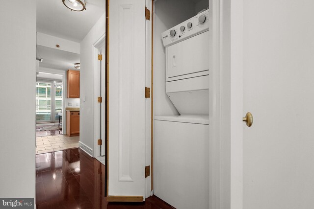 laundry area with dark wood-type flooring and stacked washer and dryer