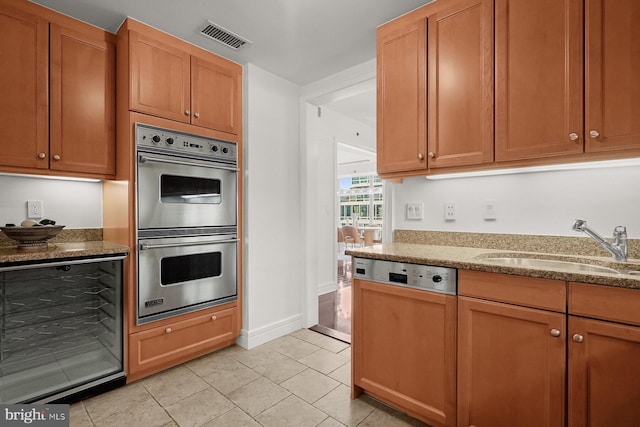 kitchen with stone countertops, sink, double oven, and light tile patterned flooring