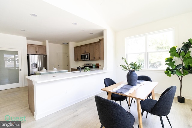 kitchen with kitchen peninsula, light wood-type flooring, sink, and appliances with stainless steel finishes