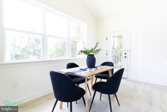 dining area with light wood-type flooring and vaulted ceiling