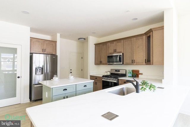 kitchen featuring light wood-type flooring, appliances with stainless steel finishes, a center island, and sink