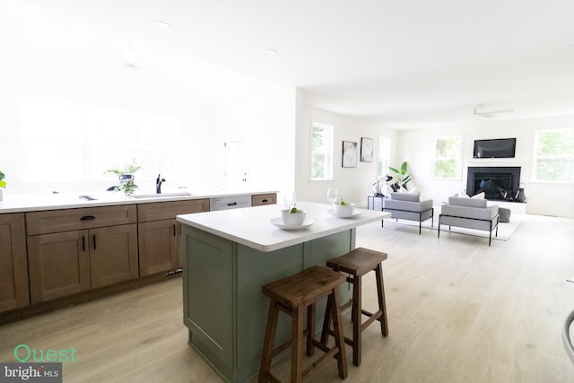 kitchen featuring a breakfast bar, sink, a center island, and light wood-type flooring