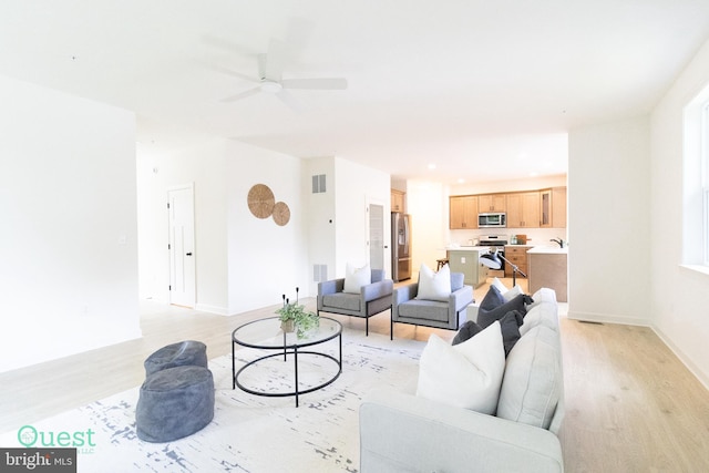 living room with light hardwood / wood-style flooring, ceiling fan, and sink