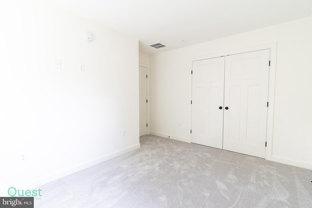 unfurnished bedroom featuring a closet and light colored carpet