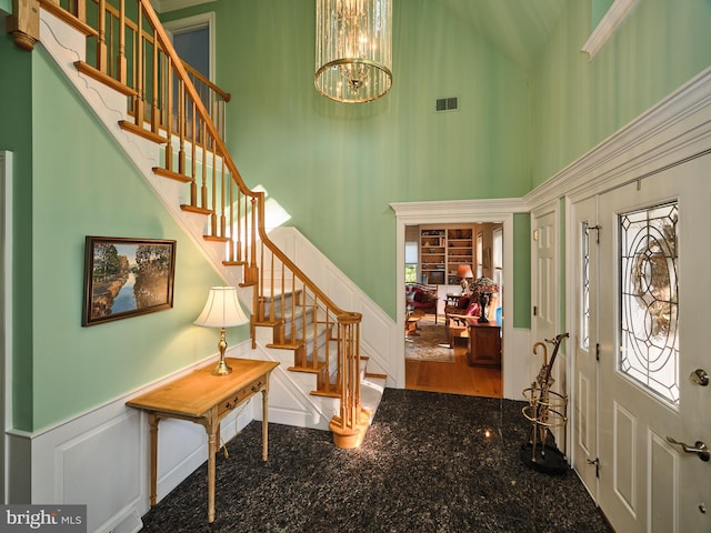 foyer entrance with a high ceiling, hardwood / wood-style flooring, and an inviting chandelier