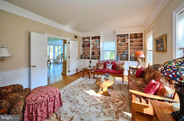 living room featuring built in features, ornamental molding, and light wood-type flooring