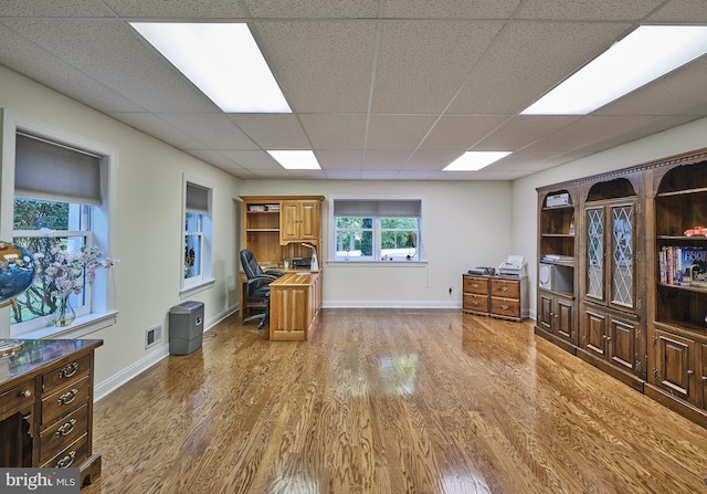 home office featuring wood-type flooring and a paneled ceiling