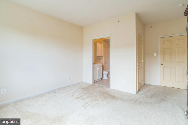 unfurnished bedroom with light colored carpet and connected bathroom