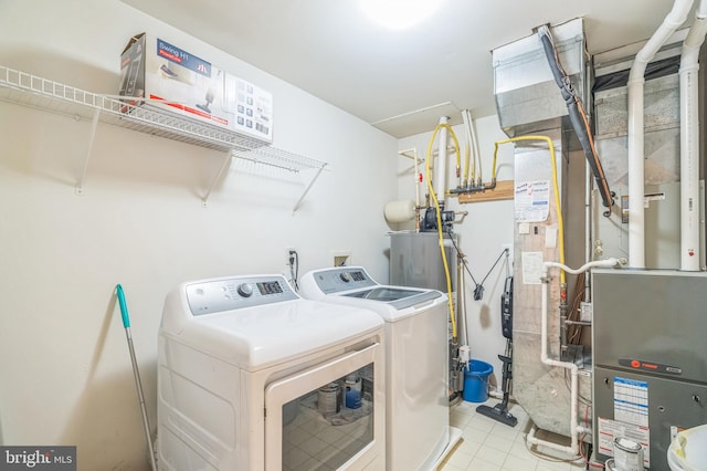 clothes washing area featuring washing machine and clothes dryer, gas water heater, and light tile patterned floors