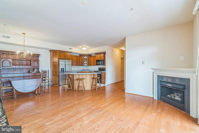 kitchen featuring light wood-type flooring, a breakfast bar area, range with gas stovetop, and stainless steel refrigerator with ice dispenser