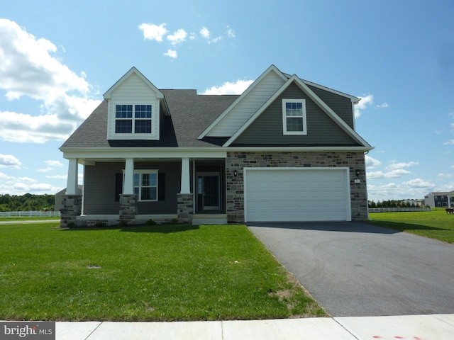 view of front of home with a front yard, covered porch, and a garage