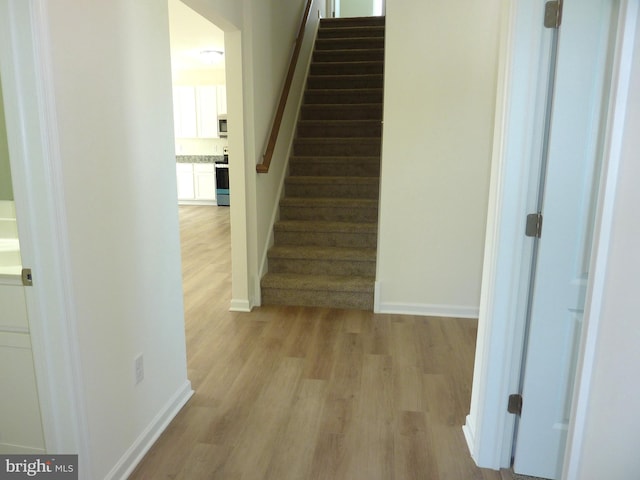 staircase with baseboards and wood finished floors