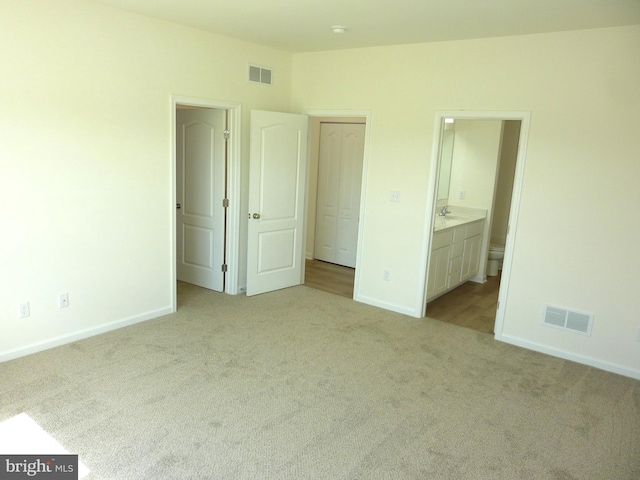 unfurnished bedroom with carpet floors, baseboards, and visible vents