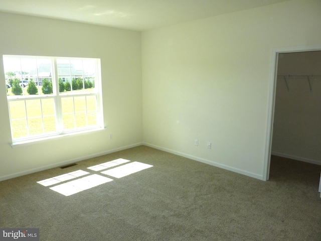 unfurnished bedroom with carpet flooring, visible vents, baseboards, a spacious closet, and a closet