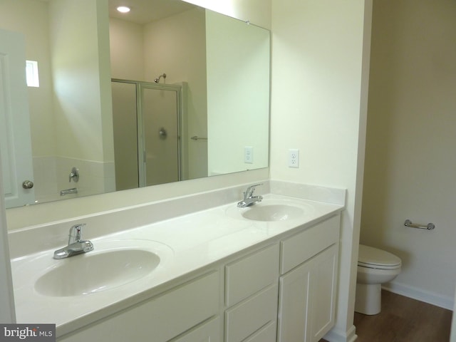 full bath with double vanity, wood finished floors, a stall shower, and a sink