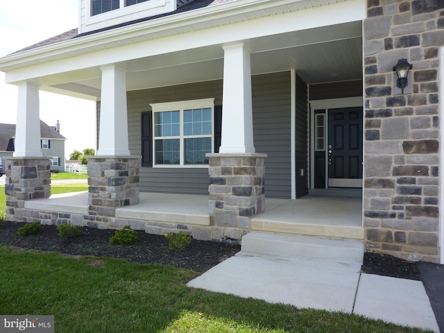 property entrance with stone siding, a shingled roof, and a porch