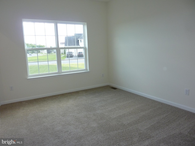 empty room featuring visible vents, baseboards, and carpet flooring