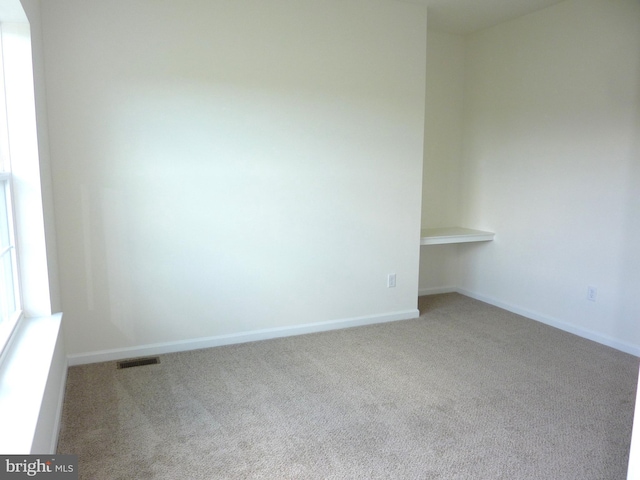 unfurnished room featuring carpet floors, visible vents, and baseboards