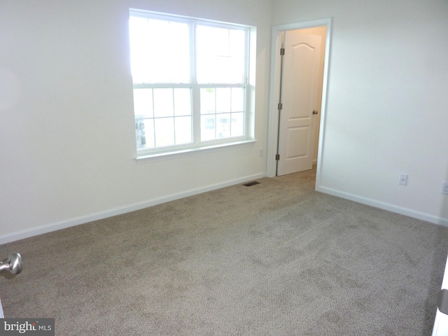 empty room with carpet floors, visible vents, and baseboards