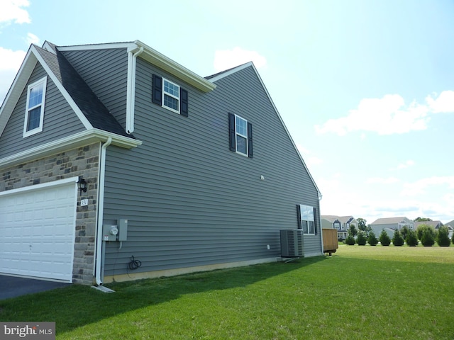 view of side of property with driveway, stone siding, cooling unit, and a yard