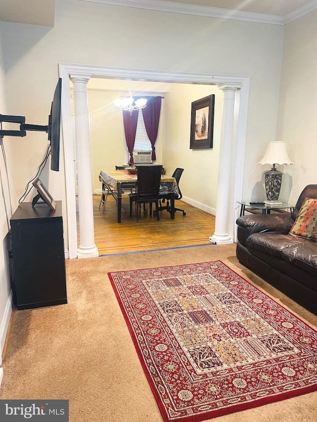 living room featuring a notable chandelier, crown molding, hardwood / wood-style flooring, and ornate columns