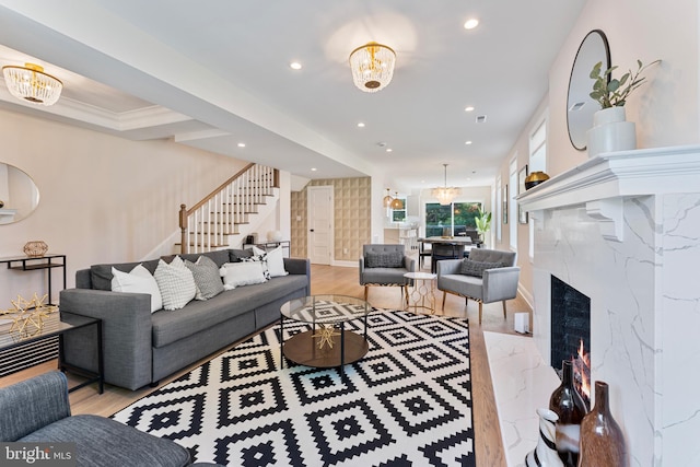 living room featuring a high end fireplace, light wood-type flooring, and a chandelier