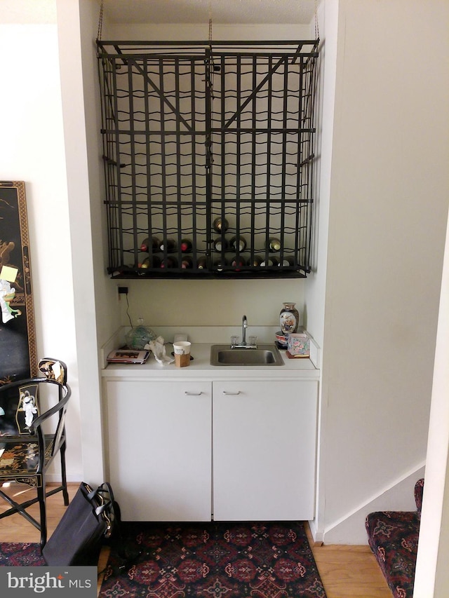 bar featuring sink, white cabinets, and light wood-type flooring